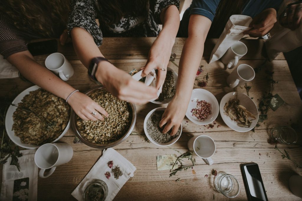 Plusieurs mains se rejoignent autour de bols de nourriture posés sur une table en bois — symbole du partage et de l'hospitalité
